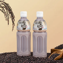 Deux bouteilles de boisson coréenne au riz noir présentées avec des épis de riz et des grains de riz noir sur un fond beige.