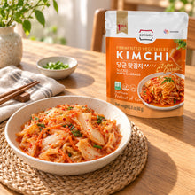 Kimchi coréen aux carottes Jongga servi dans un bol en céramique, avec son sachet de 80 g sur une table en bois baignée de lumière naturelle.