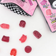 Gros plan sur les bonbons gélifiés de diverses formes (nœud, casque audio, etc.) dispersés à côté du sachet ouvert Seoju Hello Kitty Berry Ace.
