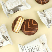 Gros plan sur un gâteau Moncher Lotte coupé en deux, révélant une crème blanche et fondante entre deux biscuits moelleux au cacao.