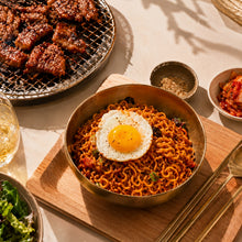 Nouilles coréennes Korean Street BBQ Poulet servies avec un œuf au plat, accompagnées de viande grillée et de garnitures coréennes.
