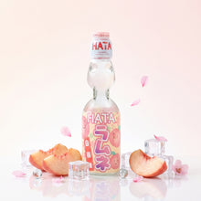 Bouteille de Ramune HATA Pêche Blanche avec éclaboussure de soda, glaçons et pêches fraîches.